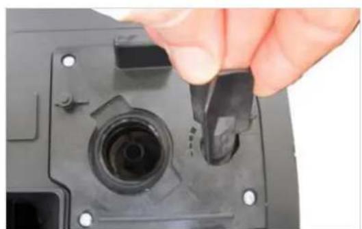 Close-up of a hand inserting a black plastic component into a black plastic housing, no text or symbols visible.