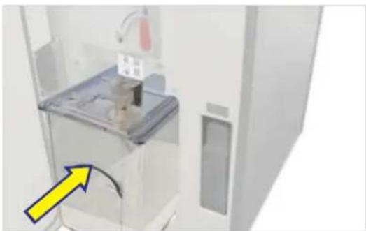 Interior view of a white appliance with a clear lid and a yellow arrow pointing to a component, no visible text or symbols.