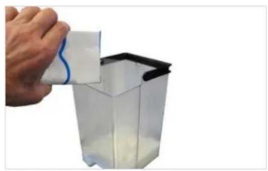 Hand pouring liquid into a transparent container with white powder, no text or symbols visible.
