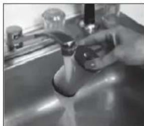 Close-up of a hand holding a faucet in a stainless steel kitchen sink (no visible text or symbols)