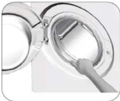 Close-up of a hand inserting a circular device into a large appliance (no visible text or symbols).