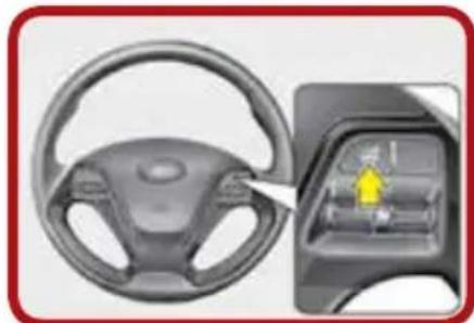 Top-down view of a car steering wheel and dashboard, with a close-up inset showing the interior panel (no text or symbols visible)