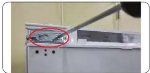 Close-up of a kitchen appliance with a tool inserted, showing a red-circled component (no visible text or symbols)