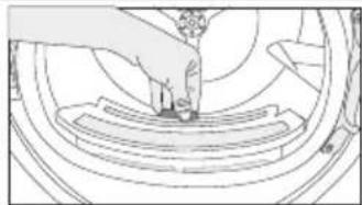 Line drawing of a mechanical assembly with a hand pressing a component on a circular base (no text or symbols).