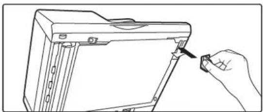 Line drawing of a hand inserting a small object into a device component (no text or symbols).