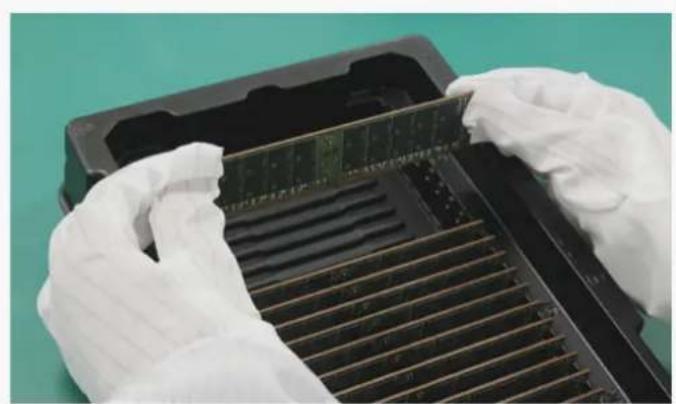 Close-up of gloved hands installing a memory card into a rack (no visible text or symbols)