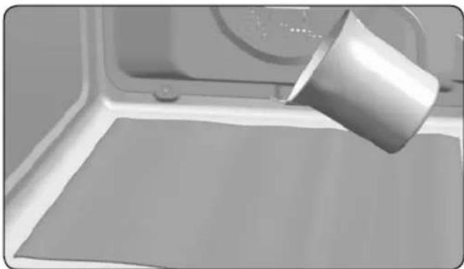 Close-up of a metal cup pouring liquid onto a flat surface inside a microwave oven (no text or symbols visible).