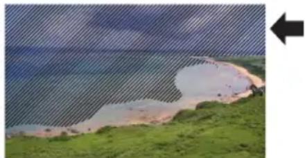 Coastal landscape with sandy shore, green grassy banks, and cloudy sky (no text or symbols)