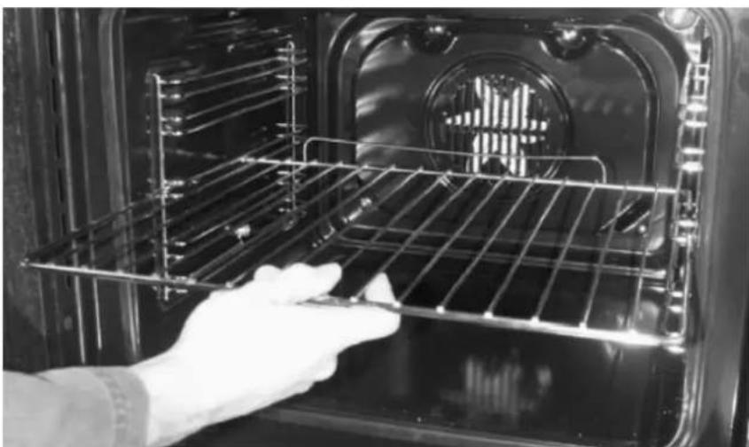 Person in gloves handling a metal rack inside an oven (no visible text or symbols)