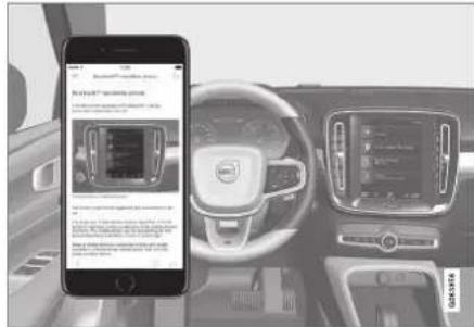 Car interior photo showing a smartphone displaying a car with a digital display, alongside the dashboard of the same vehicle.