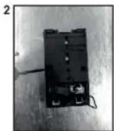Black electronic component with wires and a small inset showing a plug. No visible text or symbols.
