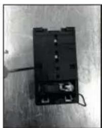 Black-and-white photo of a small electronic device with wires and connectors (no visible text or symbols).