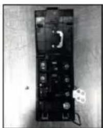 Black-and-white photo of a handheld electronic device with buttons and a small white object on the right (no visible text or symbols)