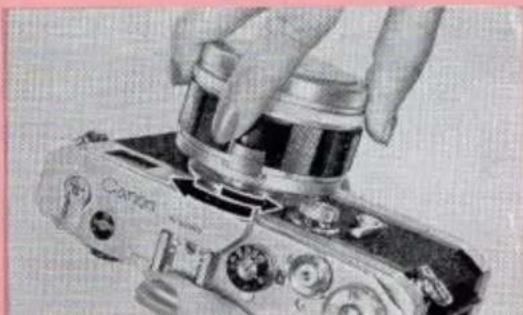 Close-up of a hand using a camera lens to adjust the lens (no visible text or symbols).