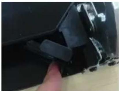 Close-up of a black plastic object being held by a finger, showing texture and surface details (no text or symbols visible)