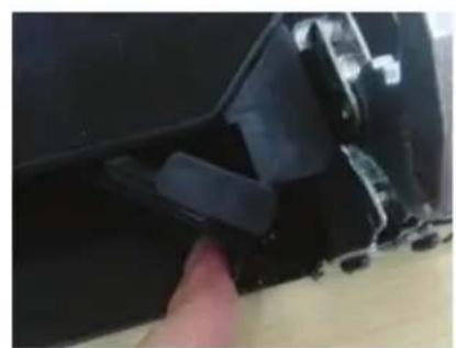 Close-up of a finger pressing down on a damaged black plastic component (no text or symbols visible).