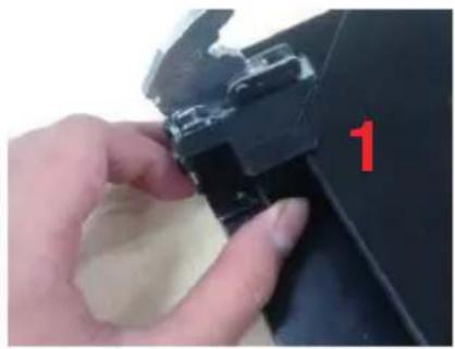 Close-up of a hand holding a black plastic clip with a red number '1' on the handle (no text or symbols on the clip itself)