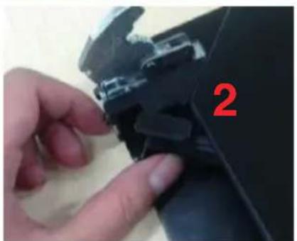 Close-up of a hand adjusting a black mechanical component with a red number '2' visible (no text or symbols on the object itself)