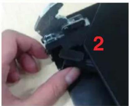 Close-up of a hand adjusting a black mechanical component with a red number '2' visible (no text or symbols on the object itself).