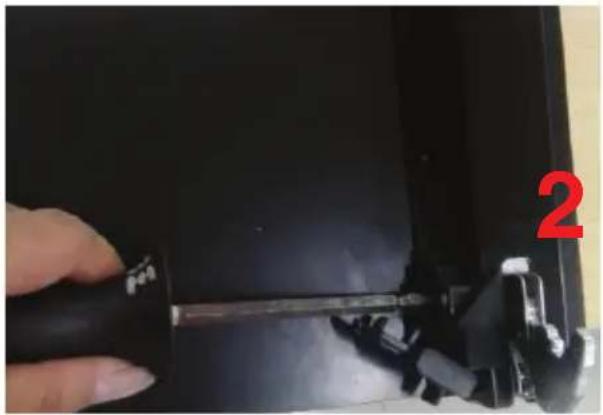 Close-up of a hand holding a screwdriver inserted into a black electronic device (no visible text or symbols)