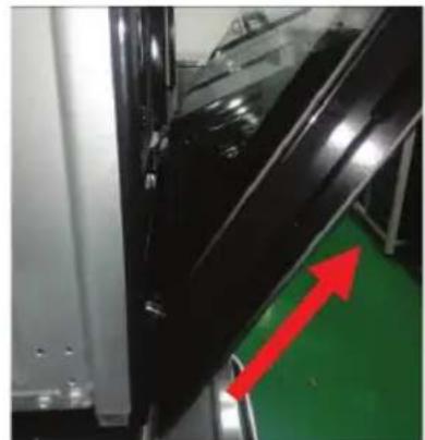 Close-up of a black plastic door with red directional arrows pointing to a green safety guard (no text or symbols visible).