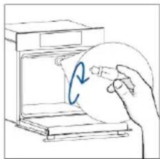 Hand holding a circular object inside a microwave oven.