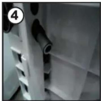 Close-up of a white plastic shelf with black cylindrical objects, no visible text or symbols