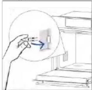 Hand inserting a small object into a device inside a circular frame (no text or symbols visible).