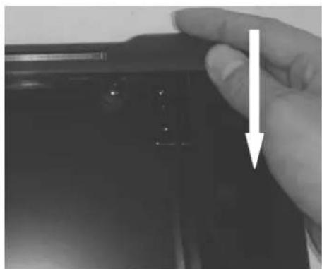 Close-up of a hand holding a black electronic device with a white arrow pointing to a button (no visible text or symbols)