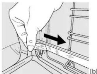 Hand pressing a component into a rail track, showing a black arrow indicating direction (no text or symbols present).