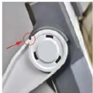 Close-up of a mechanical component with a circular dial and a red arrow pointing to a small circular feature (no text or symbols visible)