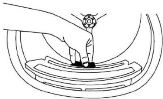 Line drawing of a hand pressing down on a car wheel rim (no text or symbols).