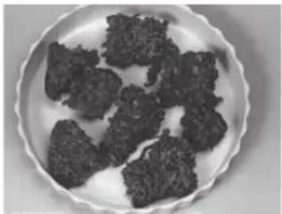 Plate of dark, irregularly shaped food items on a white background (no text or symbols visible)
