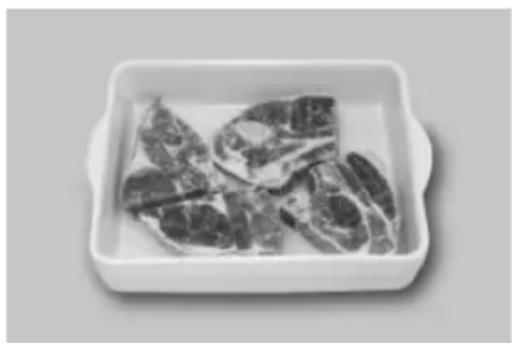 Black-and-white photo of raw meat pieces in a rectangular white bowl (no text or symbols visible)