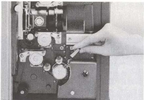 Close-up of a hand operating a mechanical device with multiple ports and a switch (no visible text or symbols)