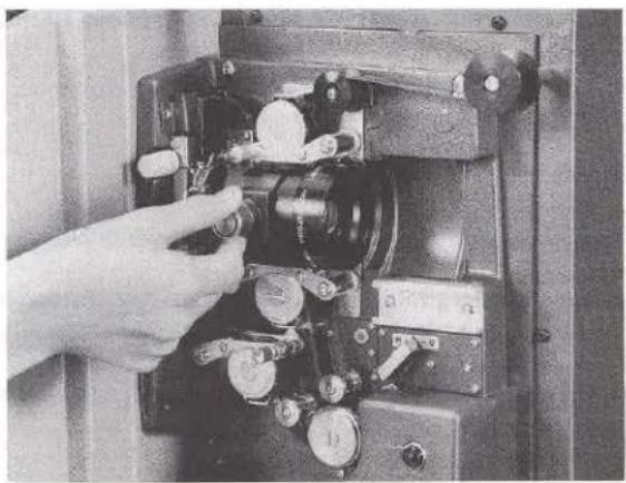 Close-up of a hand operating a mechanical device with multiple gauges and a rotary knob (no visible text or symbols)