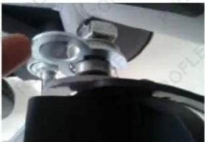 Close-up of a mechanical component with metallic parts and a hand adjusting it (no visible text or symbols)
