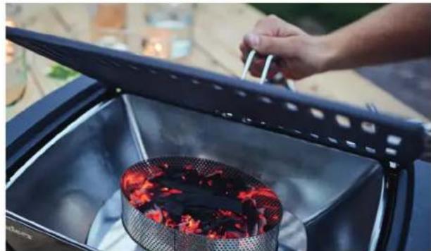 Person stirring a red flame inside a metal stove burner, with a handle open and no visible text or symbols.
