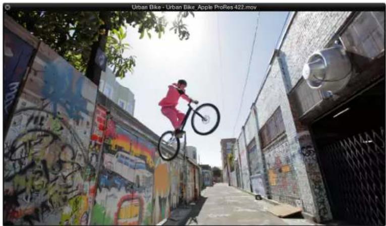Person riding a bicycle through a narrow alley between colorful graffiti-covered buildings (no visible text or symbols)