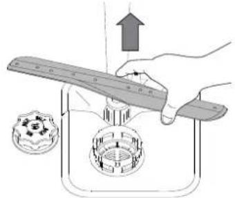 Illustration of a hand using a tool to lift a circular component with a gear-like base, no text or symbols present.