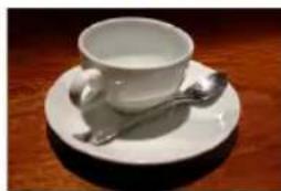 White ceramic teacup with saucer and spoon on wooden surface (no text or symbols)