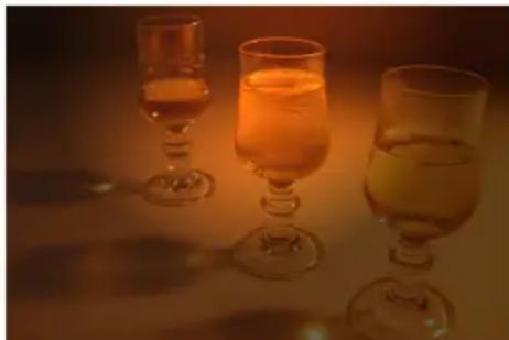 Three glasses of amber-colored liquid, arranged on a table with warm lighting (no text or symbols visible)