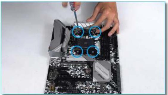 Close-up of hands using a screwdriver to adjust or install a computer motherboard with visible CPU socket and memory chips (no text or symbols)