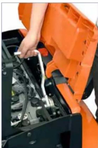 Close-up of a person adjusting an orange engine compartment with a wrench (no visible text or symbols)
