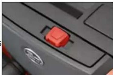 Close-up of a car's front panel with a red toggle switch and circular logo (no text or symbols visible)
