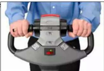 Person wearing a blue shirt and black pants holding a mechanical device with control buttons (no visible text or symbols)