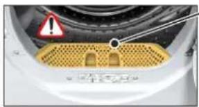 Close-up of a white appliance interior with a yellow gridded base and warning symbol (no readable text or symbols)