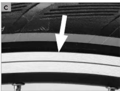 Close-up of a curved metallic component with a white arrow pointing to a feature (no text or symbols visible)