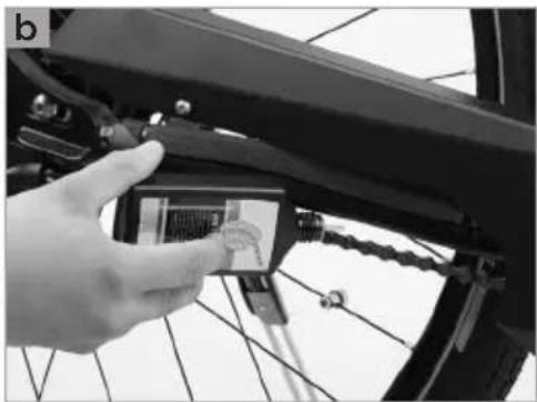 Close-up of a hand adjusting a small electronic device mounted on a bicycle frame (no visible text or symbols)