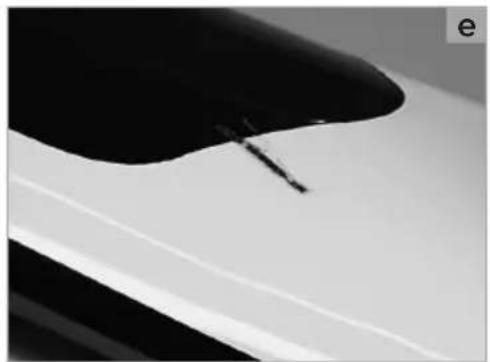 Close-up of a car's front wheel and side panel, showing black and white surfaces with a visible crack (no text or symbols)